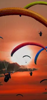 Paragliders float against a vibrant sunset sky with colorful canopies.