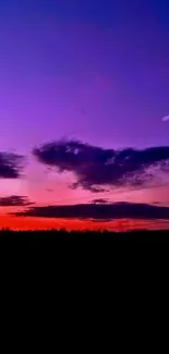 Vibrant purple and orange sunset over silhouette landscape.