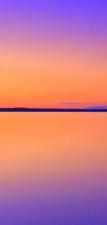 Vibrant sunset with orange and blue hues reflecting on calm water.