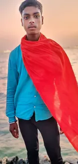 Portrait with a red scarf by the sea during a sunset, featuring vibrant colors.