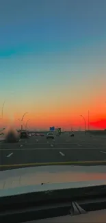 A road view at sunset with vibrant orange sky.