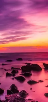 Vibrant sunset over rocky seascape with magenta and orange hues.