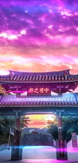 Traditional temple gateway at sunset with vibrant purple and pink sky.