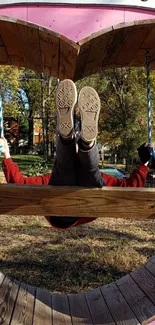 Person on a heart-shaped swing in a vibrant autumn park setting.