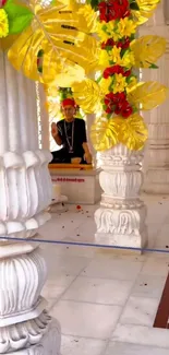 Ornate temple with yellow and red floral decor on marble pillars.