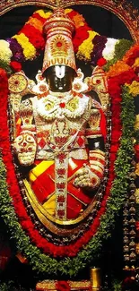 Colorful temple deity adorned with vibrant floral garlands.