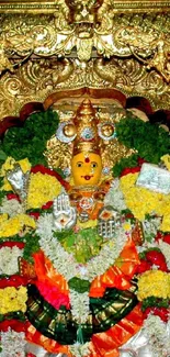 Intricate temple deity adorned with gold and colorful garlands.