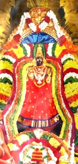 Colorful temple deity adorned in garlands with golden background.