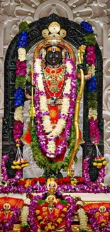 Vibrant deity adorned with colorful garlands in a temple setting.