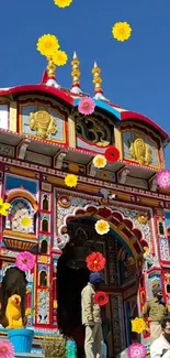 Colorful temple with vibrant floral decorations and blue sky backdrop.