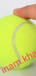 Close-up of a vibrant yellow tennis ball held by two fingers.