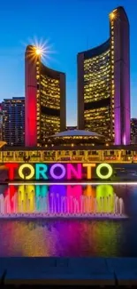 Toronto cityscape at night with colorful skyline reflected in water.