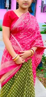 Bright pink sari with intricate designs, paired with green accents.