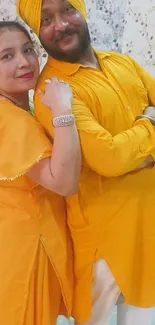 Couple in vibrant yellow traditional attire posing cheerfully.