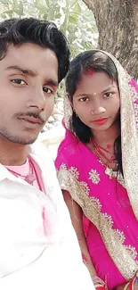 Couple in vibrant traditional attire posing outdoors.