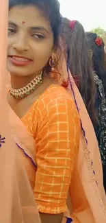 Woman in vibrant traditional attire with peach tones.