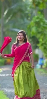 Woman in vibrant traditional attire outdoors in lush green setting.