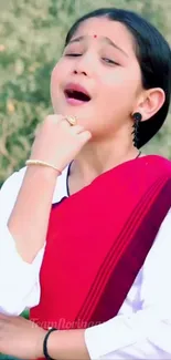 Child in vibrant traditional red attire singing.