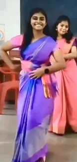 Women dancing in vibrant saris, smiling joyfully.