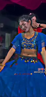 Traditional dancer in vibrant blue attire, smiling and posing gracefully.