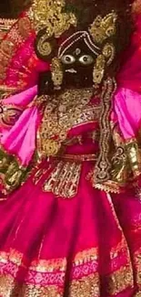 Vibrant traditional deity in pink attire with intricate gold details.