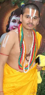 Man in yellow traditional attire with colorful beads and spiritual backdrop.