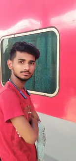 Young man in red by a vibrant train.