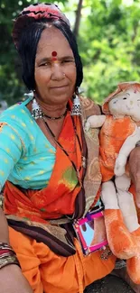 Tribal woman holding a doll with vibrant attire and background.