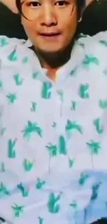 Person wearing tropical print shirt with palm motifs.