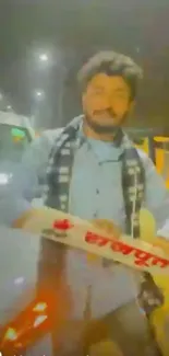 Man holding sign at night under city lights.