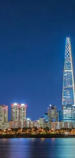 Night view of city skyline with illuminated skyscrapers and water reflections.