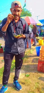 Man enjoying food at a vibrant street market.