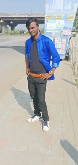 Stylish individual in blue shirt with urban background.