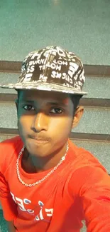 Young man in a red shirt and stylish cap standing on stairs.