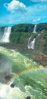 Vibrant waterfall with rainbow over lush green forest.