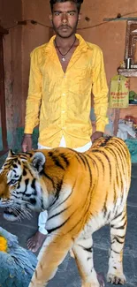 Man posing indoors with tiger and parrot.