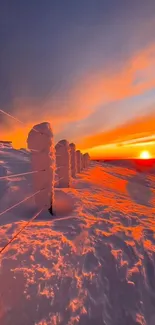 Vibrant sunset over snow-covered landscape, glowing orange sky.