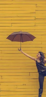 Woman with umbrella leaping against a vibrant yellow wall.