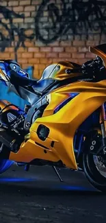 Yellow motorcycle with graffiti backdrop on street at night.