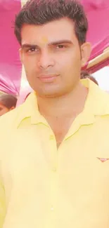 Man in a yellow shirt smiling at a festive event.