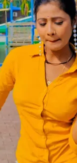 Portrait of a woman in a mustard yellow shirt with colorful background.