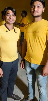 Group of friends in yellow shirts smiling indoors.