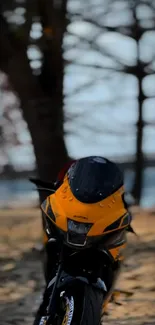 Yellow motorcycle parked under trees.