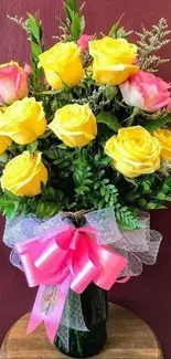 Bouquet of yellow roses with pink accents and pink ribbon.