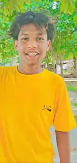 Young person in a vibrant yellow shirt surrounded by greenery.