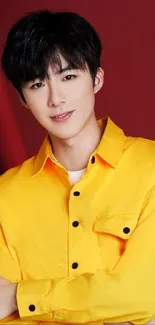 Person wearing a bright yellow shirt with red background.