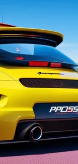 Vibrant yellow sports car on road with sleek design and blue sky backdrop.