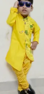 Person in vibrant yellow traditional attire with sunglasses.