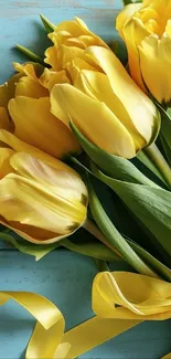 Vibrant yellow tulips on teal wood background.