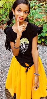 Young girl in yellow skirt outdoors with greenery.